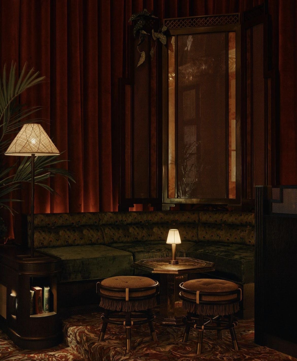 A warm, red-toned interior with a lamp, lounge seating and a framed textile panel.